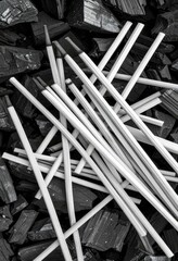 Wooden sticks arranged on a pile of charcoal Monochrome image black and white