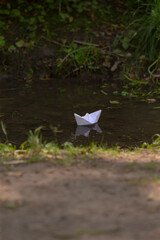 A delicate paper boat is gently floating on the surface of a serene body of water, showcasing its...