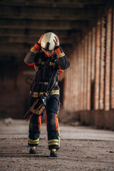 Standing in the abandoned building. Firefighter in professional equipment is indoors