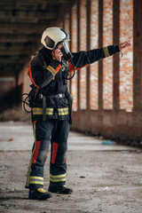 Standing in the abandoned building. Firefighter in professional equipment is indoors