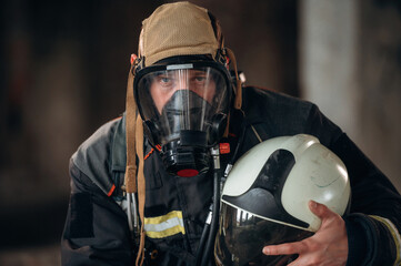 Front view, in the mask. Firefighter in professional equipment is indoors in abandoned building