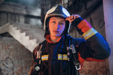 Looking forward, standing. Firefighter in professional equipment is indoors in abandoned building