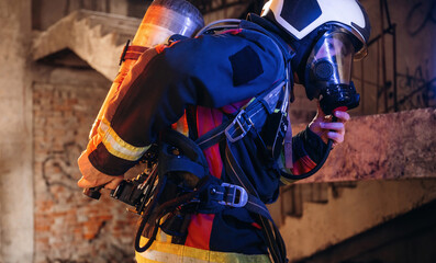 View from the side, with air balloons and mask. Firefighter in professional equipment is indoors in...
