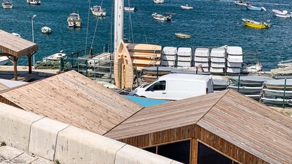 Serene coastal harbor scene with rustic wooden shacks, reflecting nautical charm and maritime...