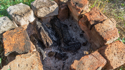 A fire pit with wooden coals. The hearth is lined with orange bricks and coals inside, top view