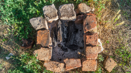 A fire pit with wooden coals. The hearth is lined with orange bricks and coals inside, top view