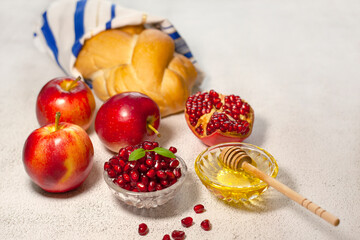 Rosh Hashanah, the Jewish New Year. Traditional symbols are tallit, apples, pomegranate, hala bread and honey on a light background. Happy Rosh Hashanah. Shana Tova