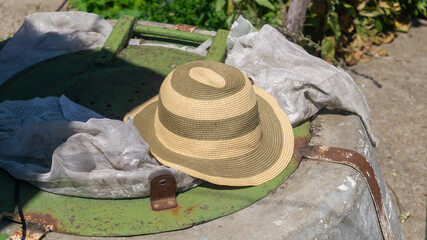 Summer hat with stripes in the sunlight on an iron bassinet lid. A summer headdress. Headdress in...