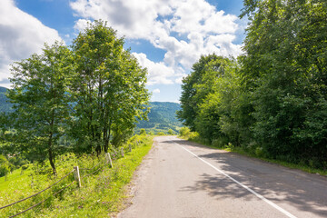 road through mountain landscape in summer. countryside nature of europe with blue sky and clouds