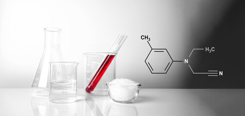 Microcrystalline wax in glass container place next to beaker, test tube and erlenmeyer flask. The...
