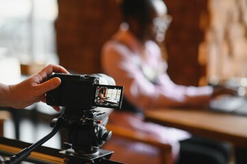 Young african female blogger with laptop recording video on camera at cafe