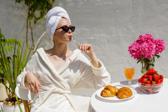 Luxury Spa Breakfast Outdoors with Croissants, Strawberries, Woman Relaxing in Towel and Sunglasses