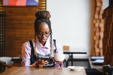 Smiling woman using smart phone in a modern cafe