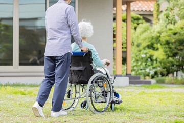 住宅の前を歩く車椅子に乗ったシニア夫婦
