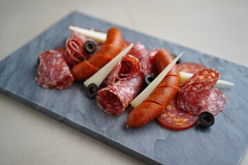 Delicious charcuterie board with assorted meats, cheese, and olives on a slate platter.