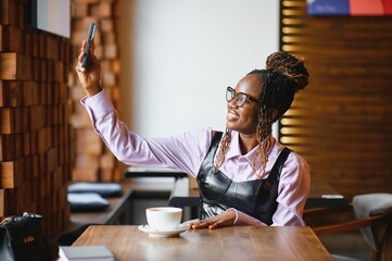 Young african woman using smart phone in a modern cafe