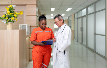 Two healthcare professional engage in discussion within a contemporary medical facility, reviewing...