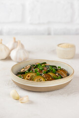 Cucumbers salad with sesame seeds, green onion, soy sauce and garlic in a bowl. Vertical orientation.
