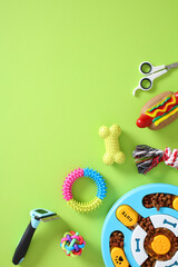 Pet care essentials arranged on green background. Includes colorful toys, grooming scissors, food...
