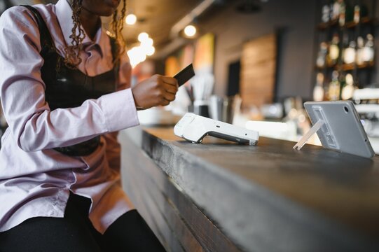 African woman paying by phone in a cafe.