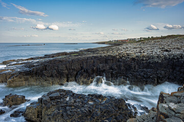 View southward to Craster with Little Carr offshore.  The rocky shore between Craster Village and Dunstanburgh Castle is an ever changing tidal environment in Northumberlands National Landscape