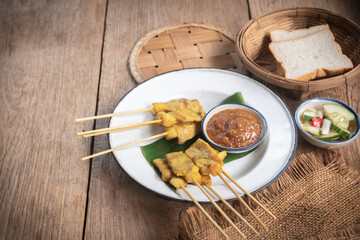 satay skewers with grilled pork and dipping sauces served on banana leaf plate