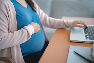 Pregnant asian woman using laptop at home pregnant businesswoman typing on laptop working on...