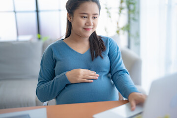 Pregnant asian woman using laptop at home pregnant businesswoman typing on laptop working on...