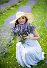 Beautiful brunette young woman In white dress and straw hat  relaxing ad holding lavender bouquet...