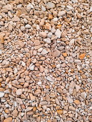 Natural stone texture with smooth pebbles in warm beige and orange tones, top view. Suitable as a neutral background or nature-themed design element.