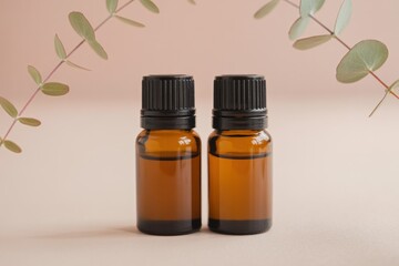 Two amber bottles with black caps surrounded by eucalyptus leaves on a light background