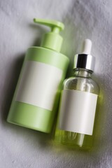 Two skincare products one in a green bottle and the other in a clear bottle with labels lying down