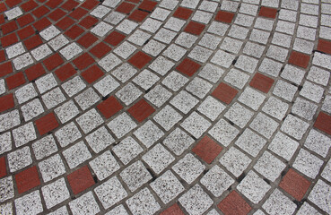 Texture of cobblestone. Pattern of sidewalk tiles in the street. Cobblestones close up. Red and gray pavement background.	