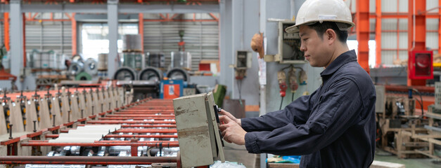 A man in a hardhat and mechanic coverall dust protection suit operates industrial equipment inside...