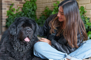 Happy young woman cuddling her big newfoundland dog at home