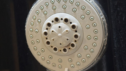 Dirty shower head with heavy limescale buildup from hard water needing cleaning