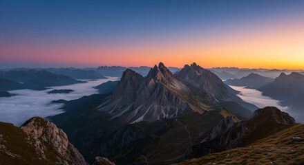 Scenic mountain range at sunrise with orange and blue sky. Clouds forming like a river in the valley below. Natural landscape for design.