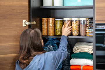 Unrecognizable girl storing peanuts container in emergency food storage pantry. 72 hour survival...