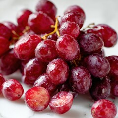 Fresh Red Grapes Bunch Close-Up with Water Droplets on White Surface for Healthy Snack and Fruit Consumption