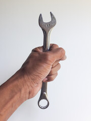 A man's hand holding a ring spanner, isolated on a white background, also known as a combination wrench.