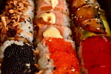 Assorted sushi rolls placed closely together. Traditional Japanese cuisine, colorful, fresh, and...