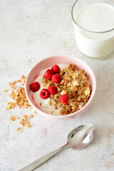 Yogurt Bowl with Granola and Raspberries and glass of milk vertical