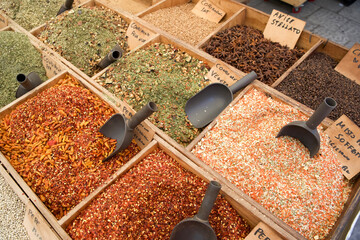 Colorful spices displayed in wooden bins at a vibrant market with scoops for easy serving and...