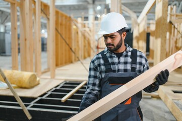 Modern modular house. Indian worker works on the construction of a wooden house
