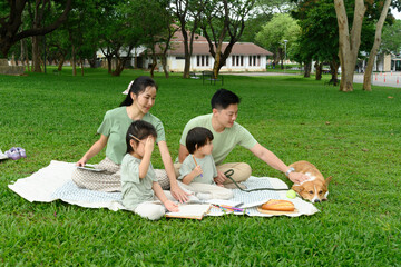 Happy Family Enjoying Time Together with Corgi Dog in the Park