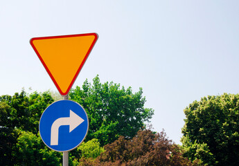 Yield sign and mandatory right turn road sign on a metal pole.Concept of traffic rules and road...