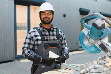Indian Carpenter works with cutting boards on sawmills for the construction of wooden modular houses