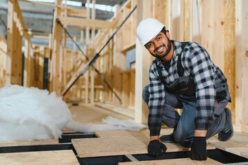 Fototapeta premium Modern modular house. Indian worker works on the construction of a wooden house