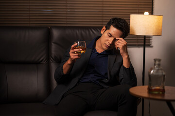 Businessman holding a glass of whiskey, sitting and drinking 