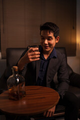 Businessman holding a glass of whiskey, sitting and drinking	
